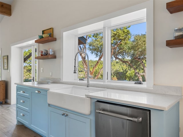 kitchen with a sink, blue cabinetry, dishwasher, and open shelves