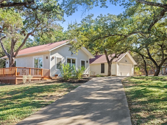 view of front of home with a wooden deck, a detached garage, and a front yard