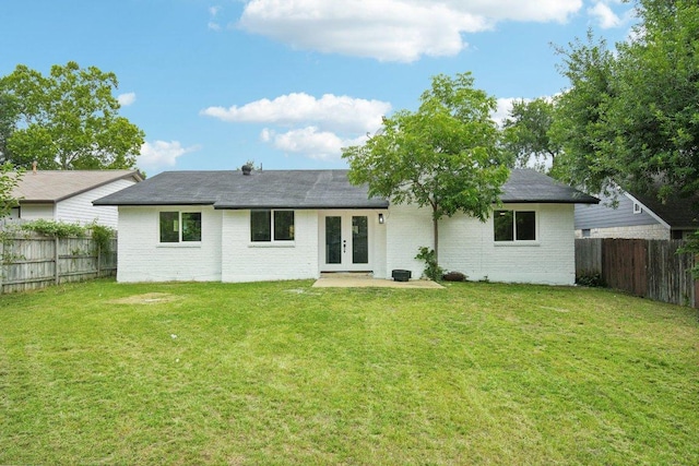 back of house with a yard, french doors, brick siding, and a fenced backyard