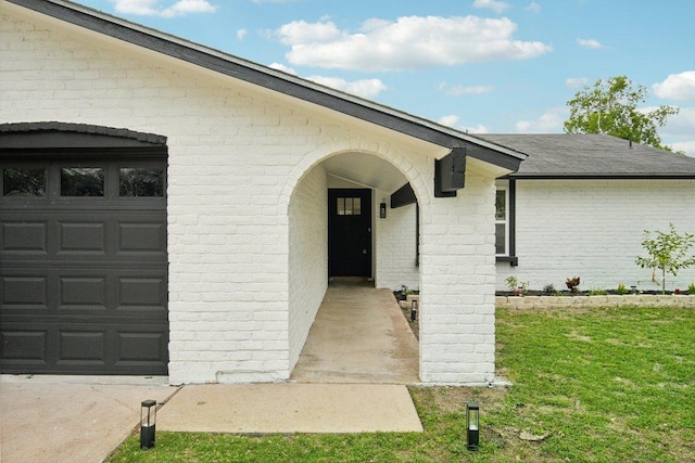 property entrance with brick siding, a garage, and roof with shingles