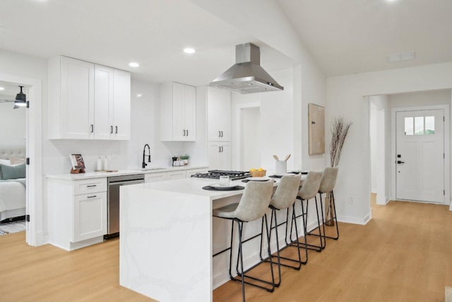 kitchen featuring extractor fan, a breakfast bar area, light wood-style flooring, appliances with stainless steel finishes, and a sink