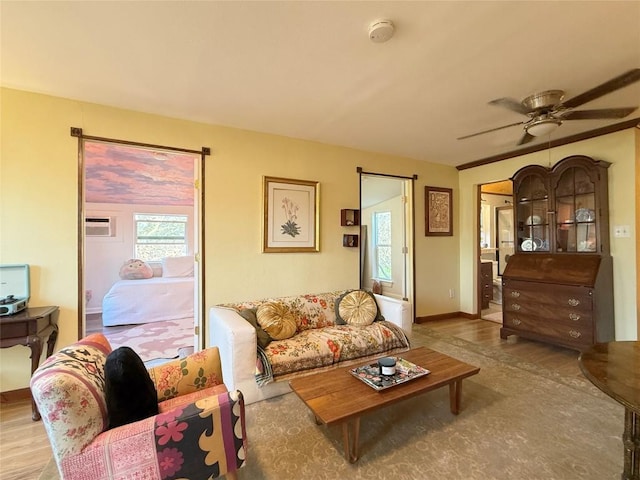 living area featuring ceiling fan, baseboards, and wood finished floors