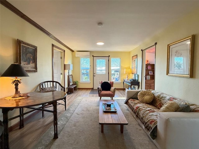 living area with ornamental molding, a wall mounted AC, baseboards, and wood finished floors