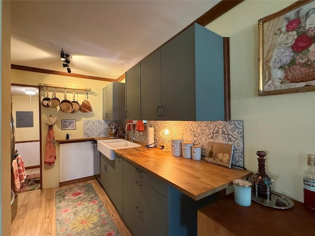 kitchen featuring gray cabinetry, a sink, wood counters, tasteful backsplash, and light wood-style floors