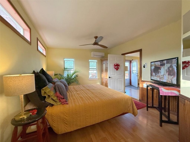 bedroom featuring ceiling fan, a wall unit AC, and wood finished floors