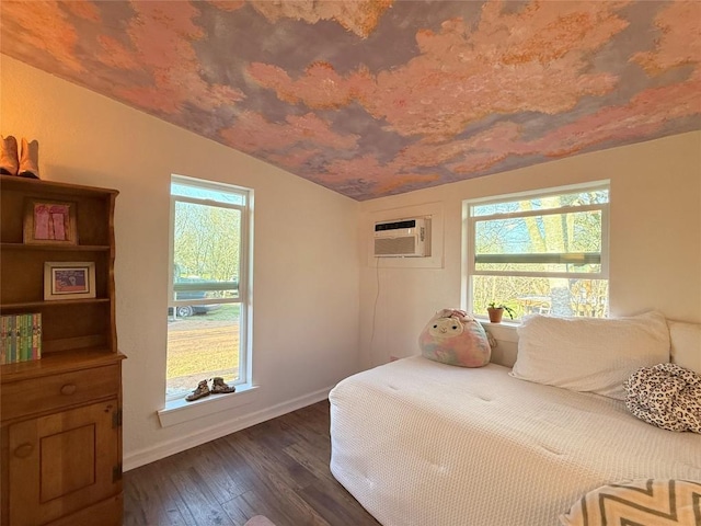 bedroom with dark wood finished floors, a wall unit AC, baseboards, and vaulted ceiling