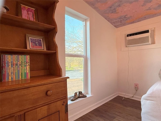 interior space featuring an AC wall unit, baseboards, and wood finished floors