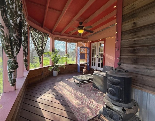 sunroom featuring lofted ceiling with beams, french doors, ceiling fan, and a wood stove