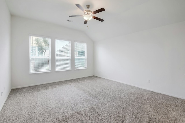 carpeted empty room featuring vaulted ceiling, a ceiling fan, visible vents, and baseboards