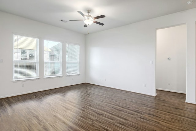 empty room with a ceiling fan, dark wood-style floors, visible vents, and baseboards