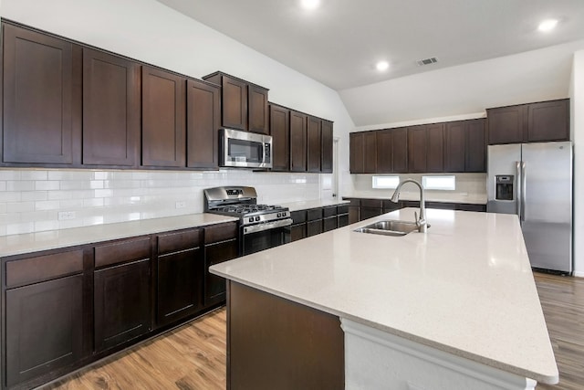 kitchen with a sink, stainless steel appliances, tasteful backsplash, and light wood finished floors