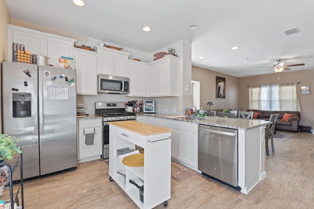 kitchen featuring visible vents, a sink, appliances with stainless steel finishes, white cabinetry, and open floor plan