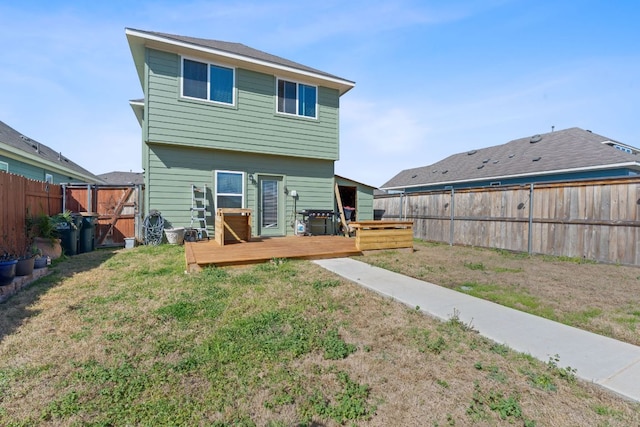 back of property featuring a fenced backyard, a deck, a yard, and a gate