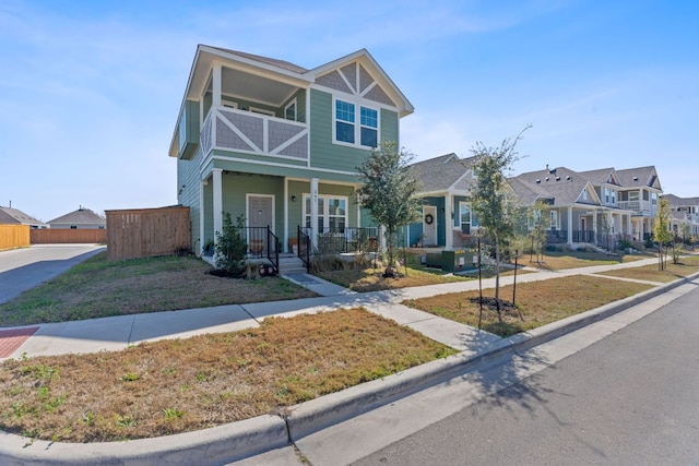 view of front of home featuring fence, a residential view, a porch, a front yard, and a balcony