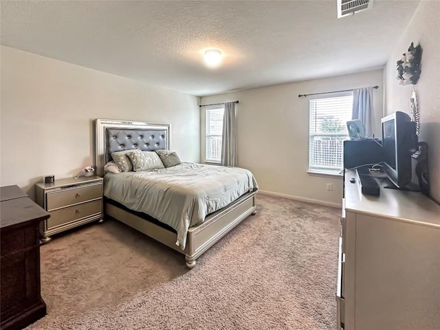 bedroom with a textured ceiling, multiple windows, visible vents, and light carpet