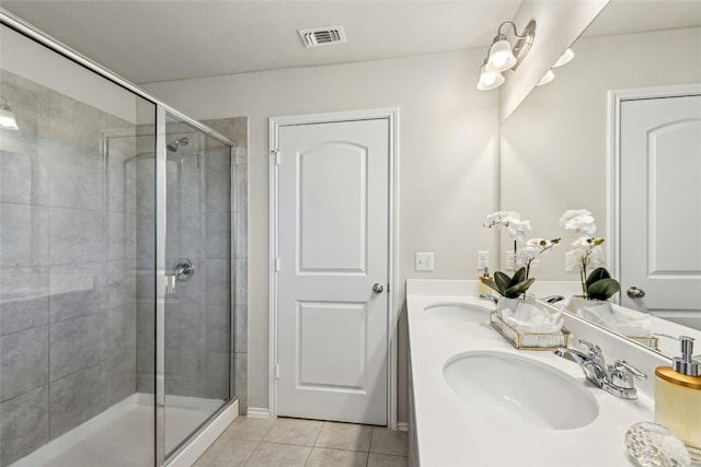 bathroom with visible vents, a shower stall, double vanity, tile patterned floors, and a sink