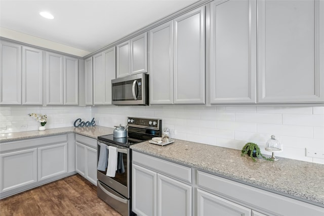 kitchen with decorative backsplash, dark wood-style floors, light stone countertops, and stainless steel appliances