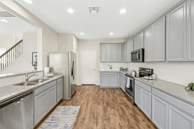 kitchen featuring visible vents, gray cabinetry, a sink, light wood-style floors, and appliances with stainless steel finishes