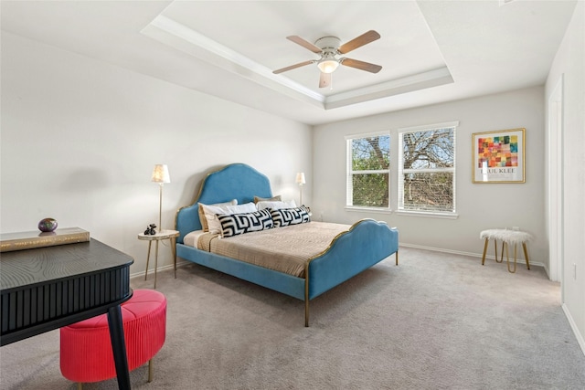 carpeted bedroom with a tray ceiling, a ceiling fan, and baseboards