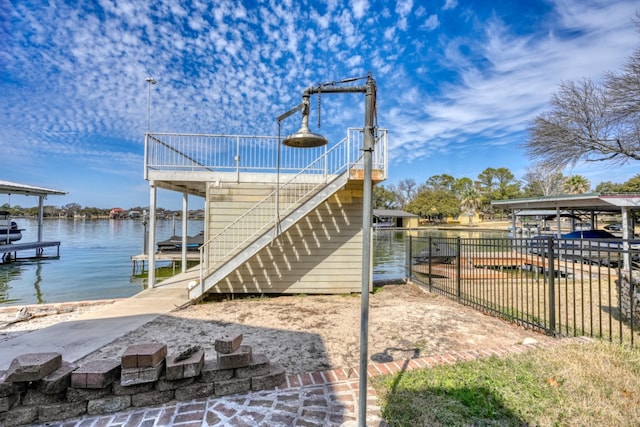 dock area with a water view, boat lift, stairs, and fence