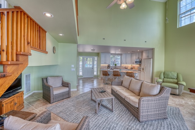 living room with baseboards, visible vents, a high ceiling, recessed lighting, and ceiling fan