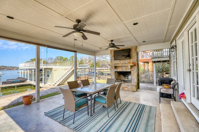 sunroom / solarium with a wealth of natural light, a water view, and an outdoor stone fireplace