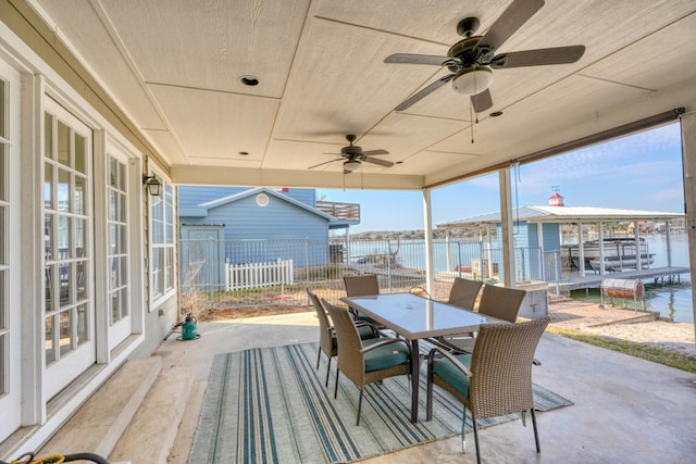 view of patio with outdoor dining area, a water view, ceiling fan, and fence