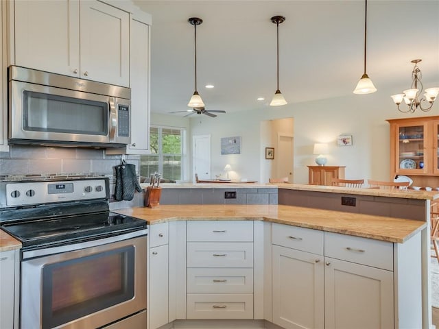 kitchen featuring tasteful backsplash, stainless steel appliances, a peninsula, white cabinets, and light stone countertops