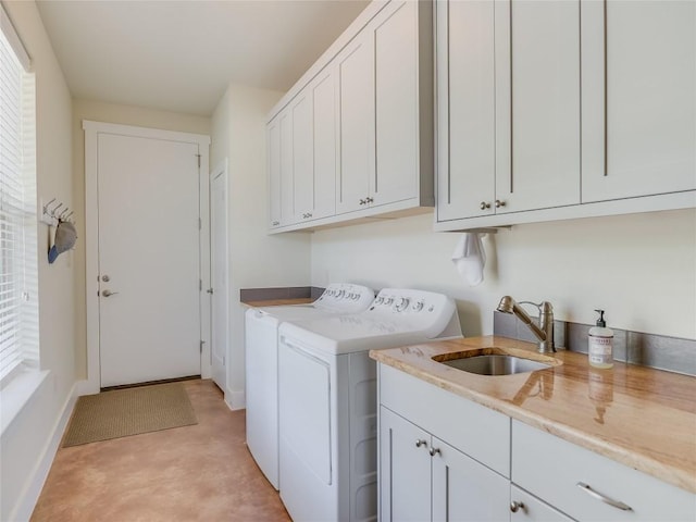 washroom featuring a sink, baseboards, cabinet space, and washer and dryer