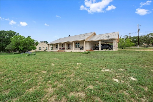 rear view of property featuring an attached carport, a porch, metal roof, and a yard