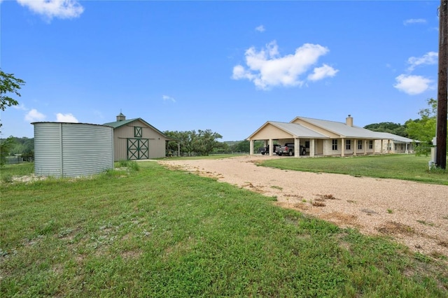 exterior space with an attached carport, an outbuilding, and dirt driveway