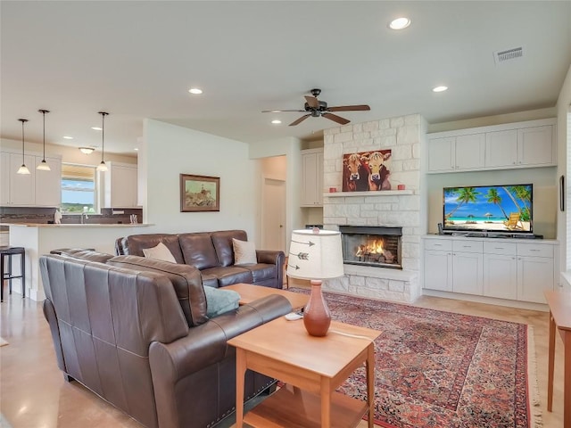 living room with recessed lighting, visible vents, a stone fireplace, and ceiling fan