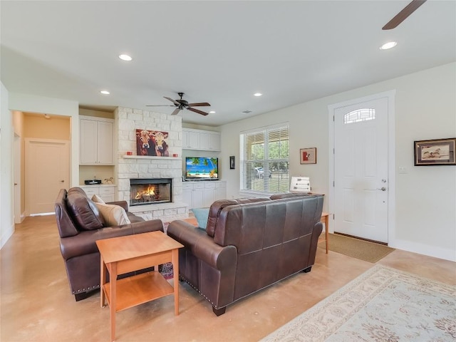 living area with a stone fireplace, recessed lighting, and concrete flooring