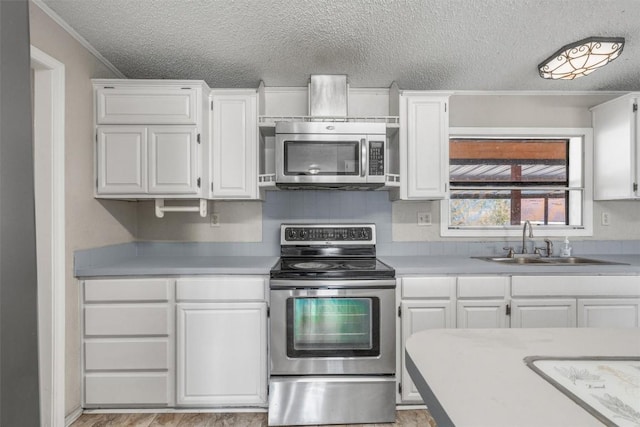 kitchen with a sink, a textured ceiling, appliances with stainless steel finishes, white cabinets, and light countertops