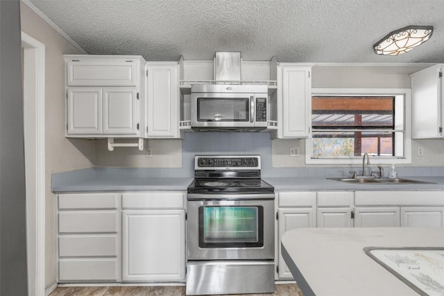 172 Hershal Ln, Cedar Creek, TX 78612 - kitchen with stainless steel appliances, a textured ceiling, white cabinetry, light countertops, and crown molding