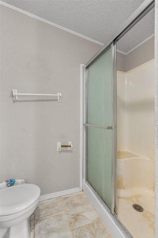 bathroom with baseboards, a shower stall, a textured ceiling, and toilet