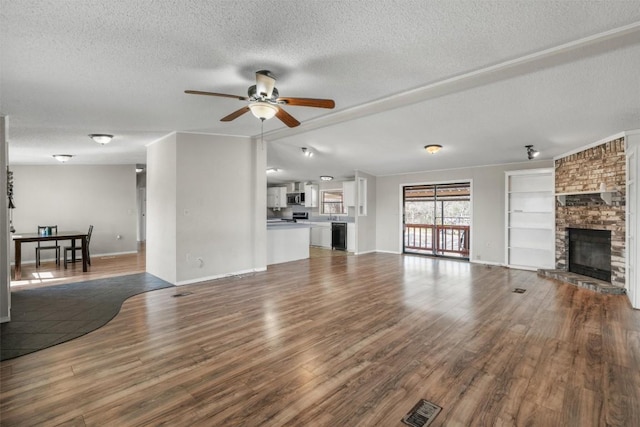 unfurnished living room featuring wood finished floors, baseboards, a fireplace, ceiling fan, and a textured ceiling