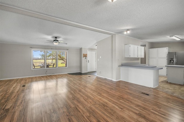 unfurnished living room with a textured ceiling, a ceiling fan, and wood finished floors