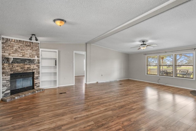 unfurnished living room with wood finished floors, a fireplace, ceiling fan, vaulted ceiling, and a textured ceiling