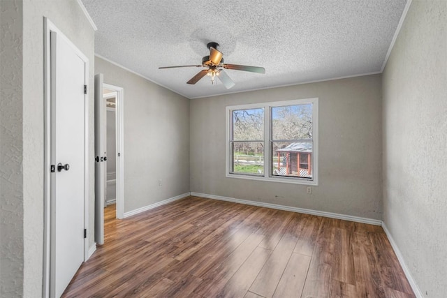 unfurnished bedroom featuring a textured ceiling, wood finished floors, baseboards, and ornamental molding