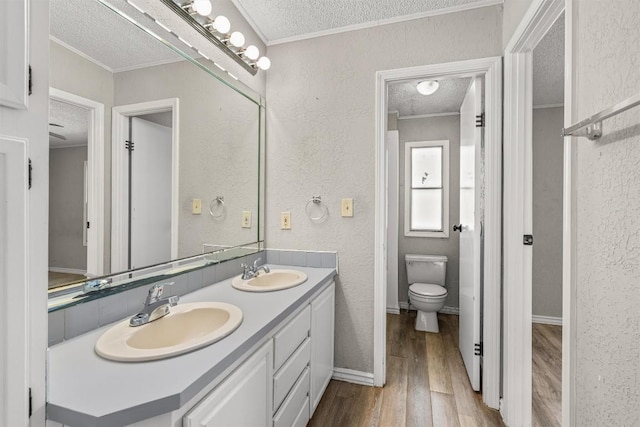 172 Hershal Ln, Cedar Creek, TX 78612 - full bathroom with a textured ceiling, double vanity, a textured wall, wood finished floors, and ornamental molding