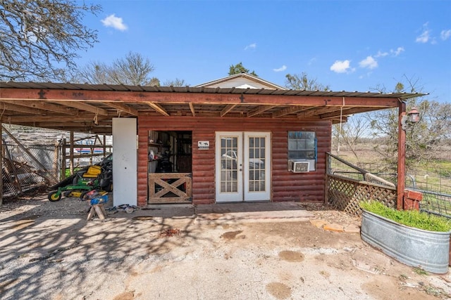 rear view of property featuring log veneer siding, an outbuilding, fence, and french doors