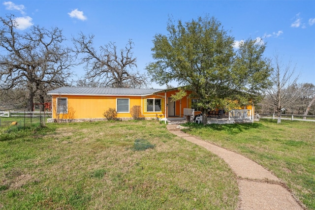 view of front of home with metal roof, a front lawn, and fence