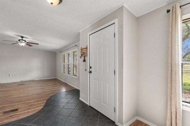 foyer with visible vents, ceiling fan, a textured ceiling, and baseboards