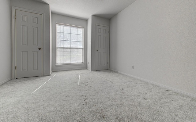 unfurnished bedroom with a textured ceiling, baseboards, and carpet floors