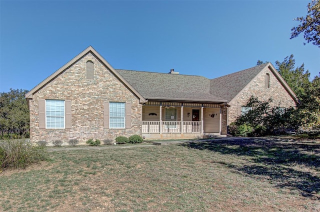 view of front of house featuring brick siding, covered porch, and a front yard