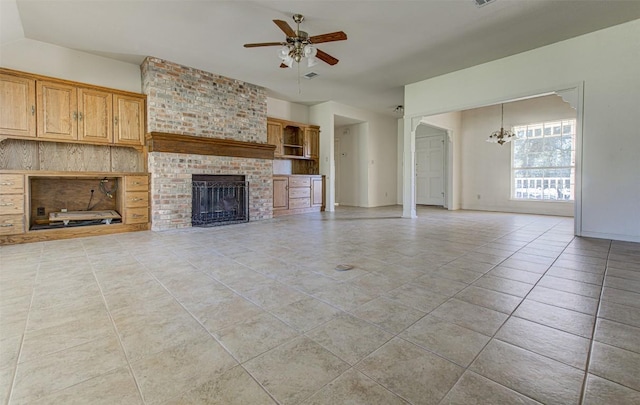 unfurnished living room featuring light tile patterned floors, baseboards, a brick fireplace, and ceiling fan with notable chandelier