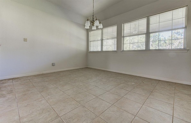 unfurnished room featuring an inviting chandelier, light tile patterned floors, and baseboards