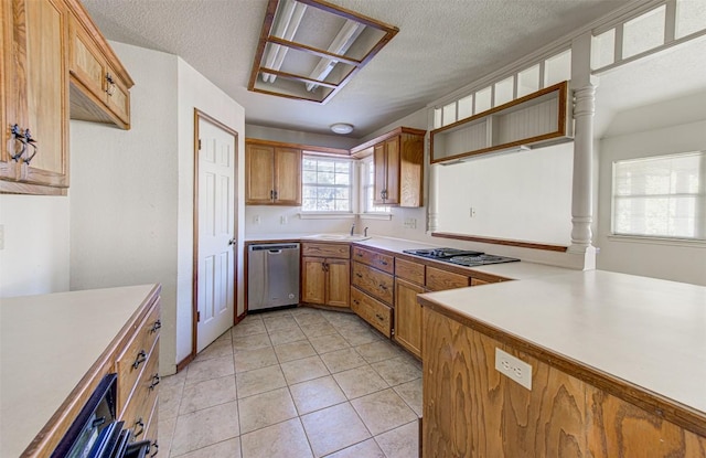 kitchen featuring light countertops, stovetop, light tile patterned floors, stainless steel dishwasher, and a sink