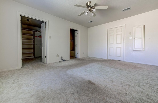 unfurnished bedroom with a spacious closet, visible vents, carpet floors, and a textured ceiling